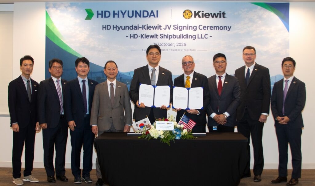 HD Hyundai and Kiewit executives stand behind a table holding signed agreements at the HD Kiewit Shipbuilding LLC joint venture signing ceremony, Oct. 22, 2026